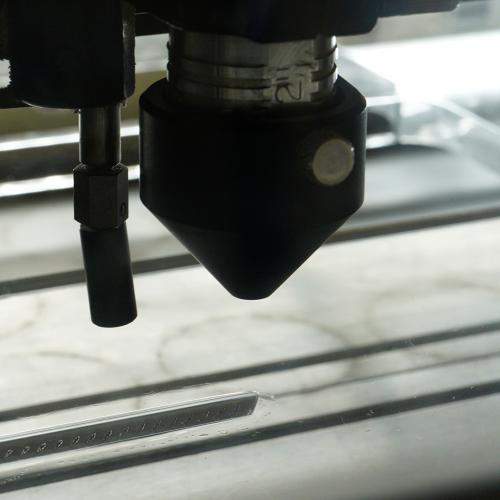Głowica laserowa zamontowana na LS 100 podczas cięcia akrylu
